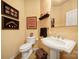 A nicely decorated powder room featuring a pedestal sink, toilet, and decor at 9332 Whistling Straits Dr, Fort Mill, SC 29707