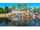 Stunning Sun City Carolina Lakes entrance with a waterfall, flowers, and mature landscaping reflecting in the water at 9332 Whistling Straits Dr, Fort Mill, SC 29707