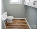 Compact half-bathroom with wood-look floors, toilet, and pedestal sink at 97 Central Ave, China Grove, NC 28023