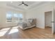 Bright bedroom features three large windows, tray ceiling, ceiling fan, and beautiful wood-look flooring at 1113 Idyllic Ln, Waxhaw, NC 28173