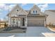 Charming home with stone accents, a gray two-car garage, well manicured flower beds, and covered front porch at 1113 Idyllic Ln, Waxhaw, NC 28173