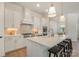 Kitchen island with seating, stainless steel appliances, pendant lights, and a decorative range hood at 1113 Idyllic Ln, Waxhaw, NC 28173