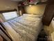 Camper bedroom with a queen-sized bed, overhead cabinet, and natural light at 113 Cedar Ln, New London, NC 28127