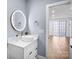 Stylish bathroom boasting a vessel sink, illuminated mirror, and a view into a bright, modern living space at 15818 Sparrowridge Ct, Charlotte, NC 28278