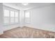 Simple bedroom with carpet, white walls and trim, and a set of three windows with shutters at 15818 Sparrowridge Ct, Charlotte, NC 28278