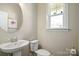 Stylish powder room featuring a round mirror and a window for natural light, creating a cozy and functional space at 182 Walking Horse Trl, Davidson, NC 28036