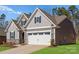 Side view of a beautiful home featuring stone accents, gray siding, and a spacious two-car garage at 2020 Canova Dr, Mount Holly, NC 28210