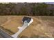New construction home featuring a paved driveway and surrounded by an undeveloped landscape and lush wooded area at 2095 Tite Rd, Stanfield, NC 28163