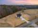 Aerial view of a modern farmhouse showing the driveway and landscaped lot surrounded by a wooded area at 2095 Tite Rd, Stanfield, NC 28163
