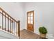 Bright entryway with wood-look flooring, wooden door, and staircase with black metal railings at 2095 Tite Rd, Stanfield, NC 28163