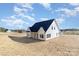 Stylish exterior of a modern farmhouse featuring a dark roof, white siding, black trim, and ample natural light at 2095 Tite Rd, Stanfield, NC 28163