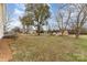 Sprawling backyard with a gravel driveway leading to outbuildings and mature shade trees at 24697 Ramsey Dr, Albemarle, NC 28001