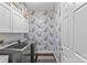 This laundry room features wallpaper, grey washer and dryer, and a patterned rug at 700 Queen Charlottes Ct, Charlotte, NC 28211
