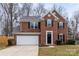 Charming two-story brick home with a well-manicured lawn, attached garage and a black front door at 10211 Ridgewell Ct, Charlotte, NC 28215