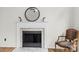 Close-up of a fireplace with a decorative mantle, round mirror, and ornate chair at 10211 Ridgewell Ct, Charlotte, NC 28215