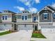 A row of new townhomes showcases varied exterior colors, stone accents, and white garages on a sunny day at 113 Alluvium Ln, Waxhaw, NC 28173