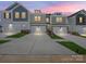 Modern townhomes featuring diverse colors, stone accents, white garages, and well-maintained lawns under a beautiful pink sky at 113 Alluvium Ln, Waxhaw, NC 28173