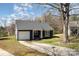 Quaint one-story home features a single-car garage, dark gray siding, and an expansive driveway at 12319 Delcorte Ln, Pineville, NC 28134