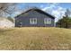 Exterior rear showcasing a home's dark siding, grassy landscape, and natural light at 12319 Delcorte Ln, Pineville, NC 28134