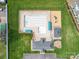 Aerial view of a community pool with a playground, lounging area, and surrounding green space at 139 Tenth Green Ct, Statesville, NC 28625