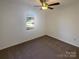 Simple bedroom featuring neutral carpet, ceiling fan, and a bright window at 14106 Carriage Lake Dr, Charlotte, NC 28273