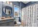 Stylish bathroom with blue textured walls, a vanity, a round mirror, and a floral shower curtain at 172 Tetcott St, Mooresville, NC 28115