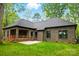 Brick home's backyard featuring covered patio and stone patio overlooking a large manicured lawn at 3738 Glen Arbor Dr, Maiden, NC 28650