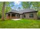 Brick home's backyard with covered patio and stone patio surrounded by a manicured lawn at 3738 Glen Arbor Dr, Maiden, NC 28650