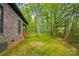Backyard of brick home with covered porch and stone patio surrounded by forest at 3738 Glen Arbor Dr, Maiden, NC 28650