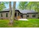 Brick home's backyard with covered patio and stone patio surrounded by large trees at 3738 Glen Arbor Dr, Maiden, NC 28650