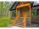 Inviting brick home entrance with a prominent wood porch featuring matching wood railing and a striking front door at 3738 Glen Arbor Dr, Maiden, NC 28650