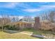 Low angle showcasing a single-story red brick home with a chimney and tidy landscaping at 3901 Starmount Ave, Charlotte, NC 28269