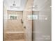 Contemporary bathroom features a glass shower stall, shower bench, and marbled tile surround at 4616 Gold Finch Dr, Denver, NC 28037