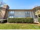 Exterior shot of condo building with light gray siding, green grass, and trimmed bushes under a clear blue sky at 4918 Sardis Rd # E, Charlotte, NC 28270