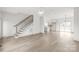 Open-concept living area featuring hardwood floors, a staircase, modern lighting, and a view of the bright kitchen at 6535 Fisher Farm Nw Ln, Concord, NC 28027
