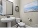 Powder room featuring a pedestal sink, toilet, and decorative artwork creating a functional and stylish space at 7205 Yellowhorn Trl, Waxhaw, NC 28173