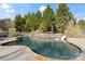 L-shaped in-ground pool with stone border and waterfall feature in the backyard at 7205 Yellowhorn Trl, Waxhaw, NC 28173