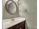 Powder room with vanity, round mirror, dark cabinets, and neutral decor at 7214 Quail Meadow Ln, Charlotte, NC 28210