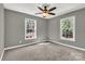 This bedroom boasts soft carpeting, natural light, a ceiling fan, and calming gray walls at 7214 Quail Meadow Ln, Charlotte, NC 28210