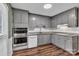 Updated kitchen features white appliances, gray cabinets, granite countertops, and hardwood floors at 7214 Quail Meadow Ln, Charlotte, NC 28210