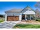 Inviting home exterior featuring a one car garage, rock landscaping, gray roof, and a welcoming porch with rocking chairs at 1013 Oakmont Dr, Rock Hill, SC 29732