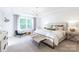 Stylish main bedroom with a tray ceiling, large window, plush bed, accent chair and decorative chandelier at 1055 Kinship Dr # 78, Lancaster, SC 29720