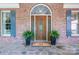 Elegant front entrance featuring a decorative wooden door, sidelights, transom window, and potted plants at 13822 Tributary Ct, Davidson, NC 28036