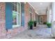 Welcoming front porch with brick facade, stone flooring, shuttered windows, and potted ferns for added charm at 13822 Tributary Ct, Davidson, NC 28036