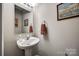 Cozy powder room featuring a pedestal sink, decorative mirror, and soft lighting at 140 Reid Ln, Pineville, NC 28134