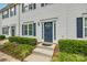 Charming townhouse entrance featuring a blue front door, dark shutters and manicured landscaping at 140 Reid Ln, Pineville, NC 28134