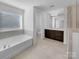 Bright bathroom featuring a soaking tub, vanity with a large mirror, and neutral tile floors at 14106 Ridgewater Way, Charlotte, NC 28278