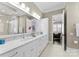 Elegant bathroom featuring dual sinks, white cabinets, marble countertop, and a glass-enclosed shower for a luxurious feel at 19604 Olde Spring Ct, Cornelius, NC 28031