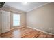 A bedroom featuring hardwood floors, neutral walls, white trim, window and white door at 2864 Sweeping Pine Ln, Denver, NC 28037