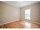 An empty bedroom featuring hardwood floors, neutral walls, white trim and a large window at 2864 Sweeping Pine Ln, Denver, NC 28037